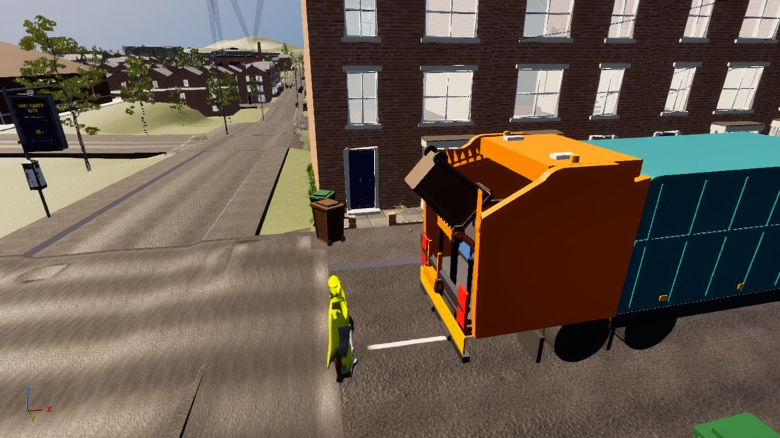 A refuse lorry seen from above at a terraced kerb, its body plain teal with no lettering and its rear loading gear orange, a loader in a bright yellow hi-vis top standing at the back of it.