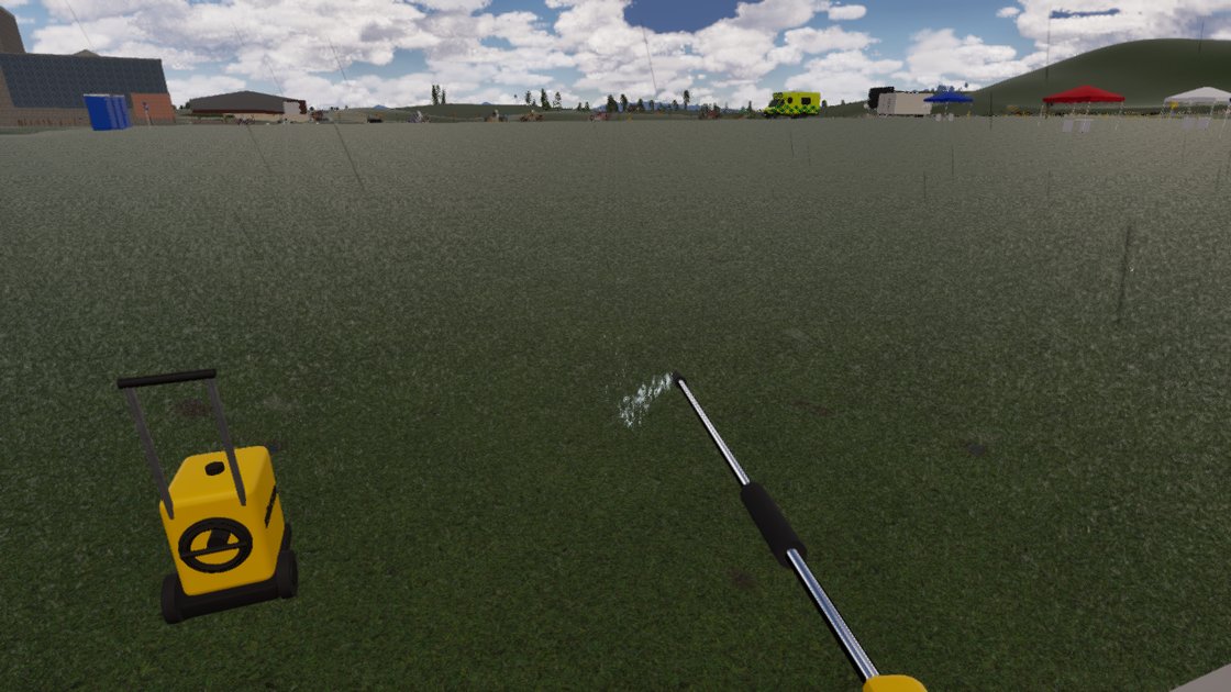 First-person view of a hand-held pressure washer lance pointing out across a grass field, with a small puff of white spray at its tip. A yellow wheeled pressure washer stands on the left, and an ambulance and gazebos are far off on the horizon.
