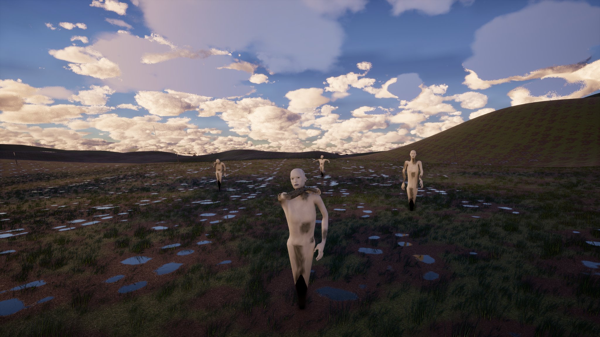 Open moorland under a big sky of white cloud, the ground dotted with puddles. Four pale, crusted human figures stand frozen at different distances on the grass, the nearest a few metres away and staring straight at the viewer.