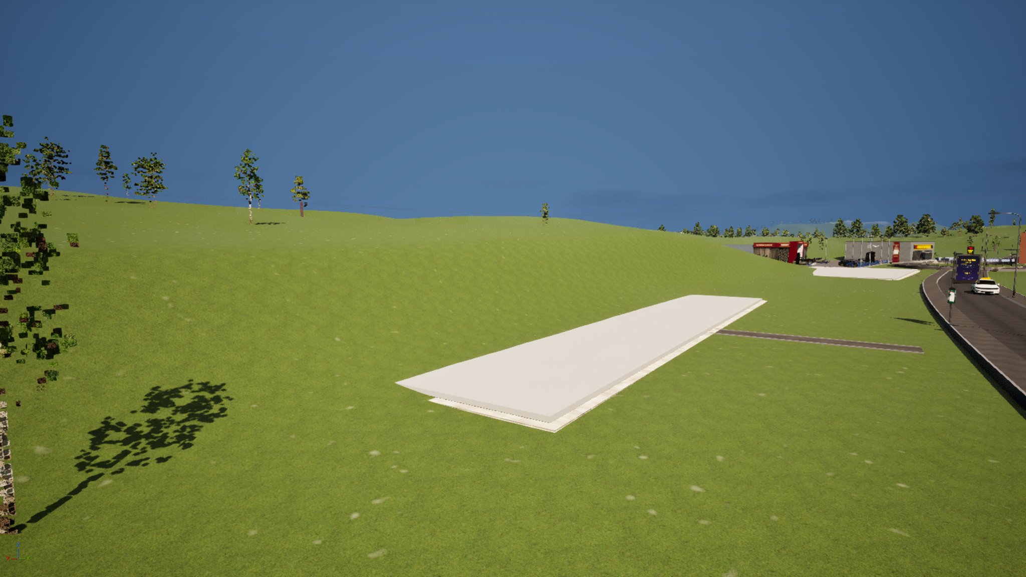 A grassy hillside beside a road with a long thin pale concrete slab showing, the rest of it buried under the slope.