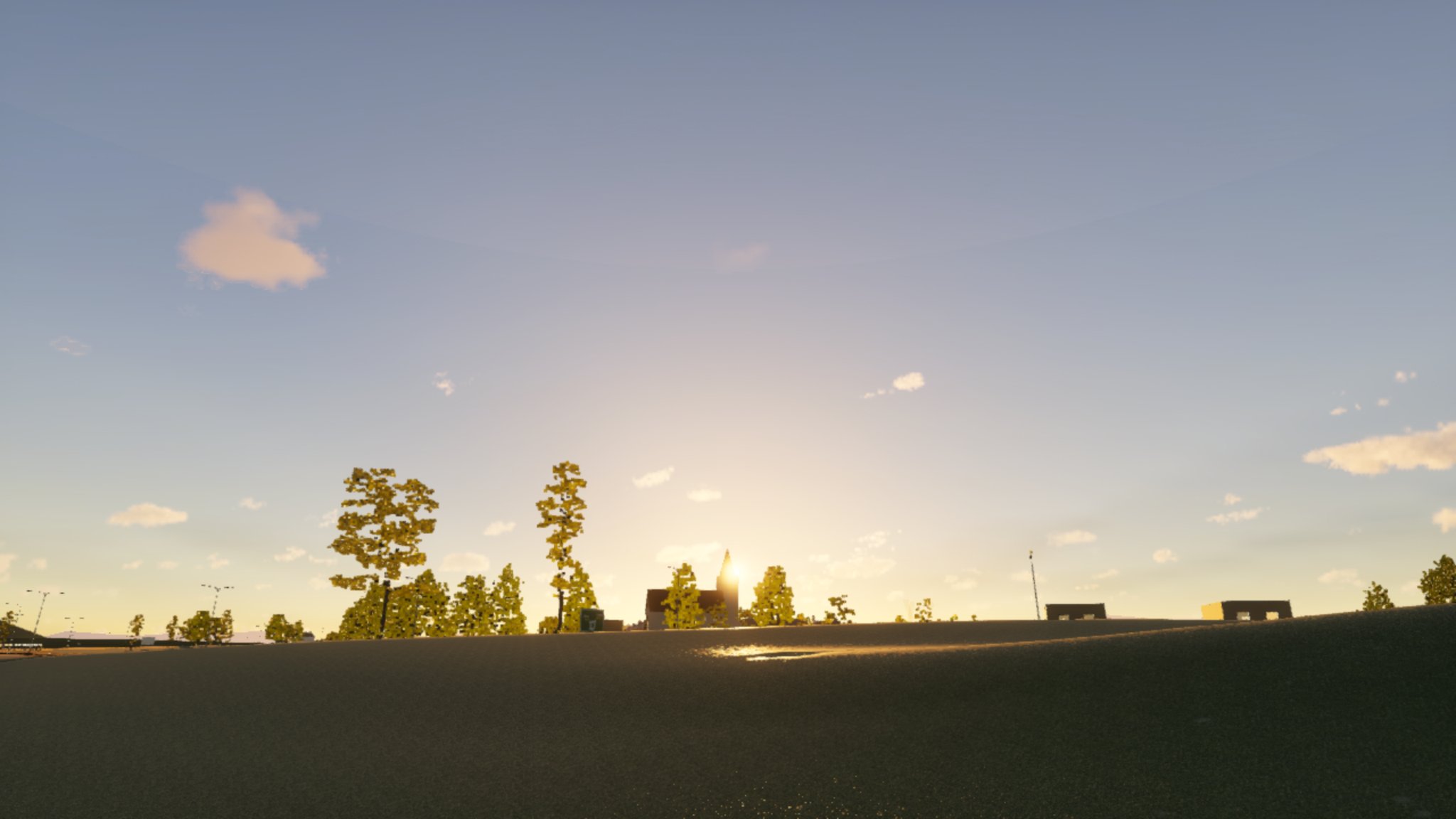 The same view at the same moment: now the sky is blue overhead and pales towards the horizon, the sun is a bright white-gold glow beside the church spire, and small clouds with warm undersides are scattered across it.