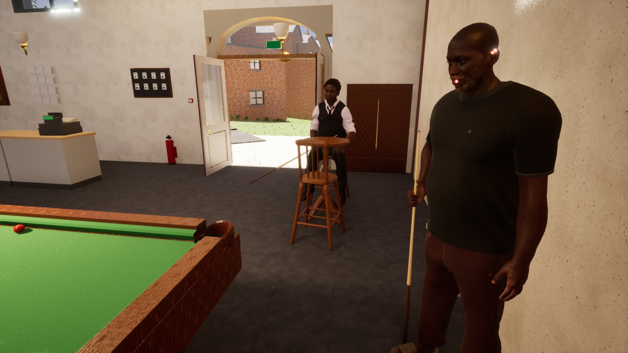 Inside the snooker hall. In the foreground on the right a bald man with a grey and ginger beard, in a black t-shirt, stands holding a cue upright. Behind him a second man in a white shirt, dark waistcoat and red tie sits on a tall wooden stool with his cue across his knees. A red ball sits at the near cushion of a green table on the left; the hall's arched doorway stands open to a sunny brick street behind them.