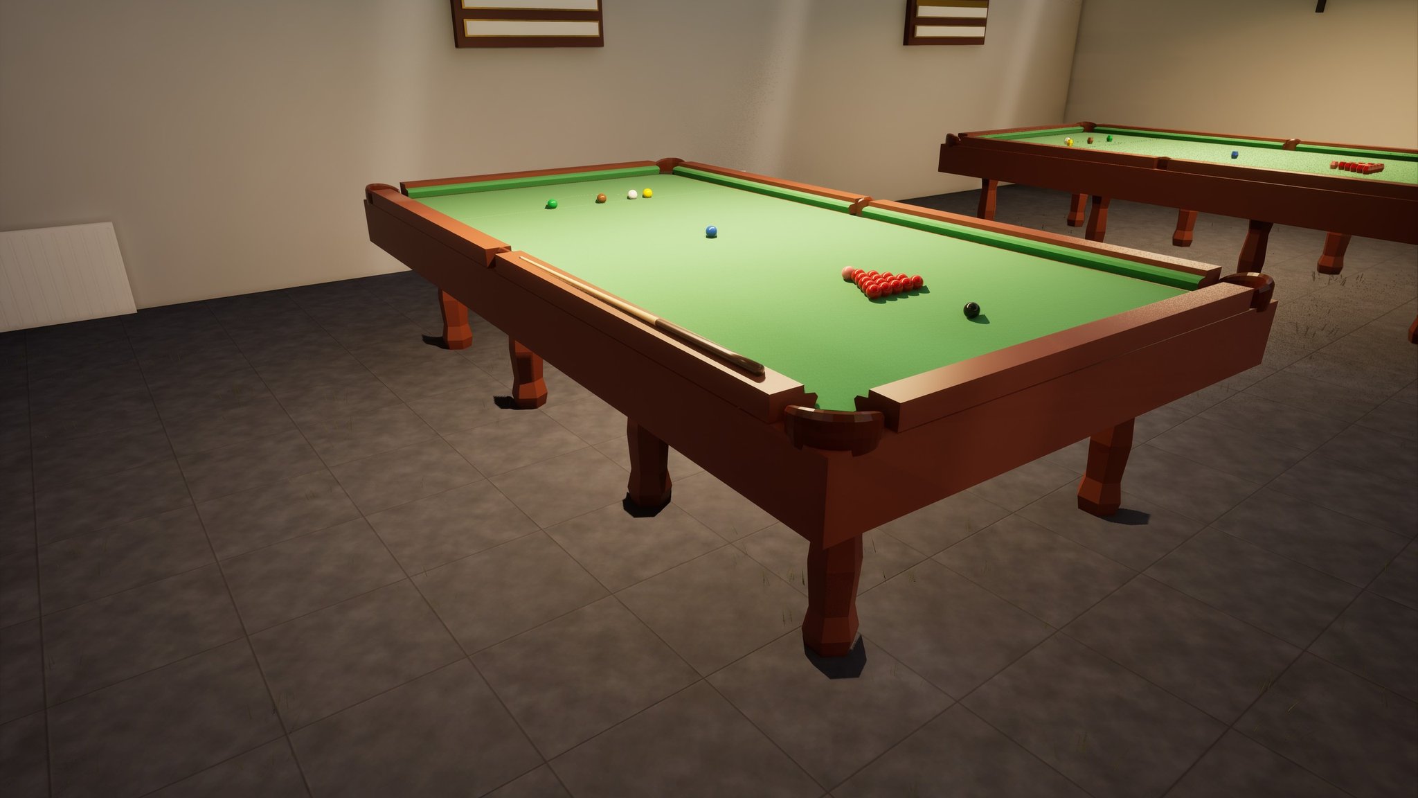 A dim snooker hall with a grey tiled floor. A full-size mahogany table with green baize stands in the foreground under a long shaded light, the fifteen reds racked in their triangle with the black below them and the baulk colours spotted at the far end. A cue lies along the cushion on the near side, and the open mouths of two corner pockets show at the near corners. A second table stands behind it against a pale wall hung with two framed honours boards.