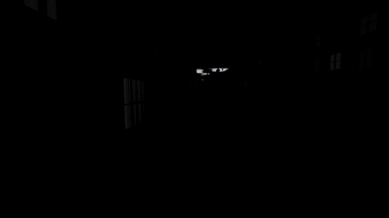 An almost completely black frame of a street at two in the afternoon. Only the faint outline of a window and a small bright patch of sky between rooftops can be made out.