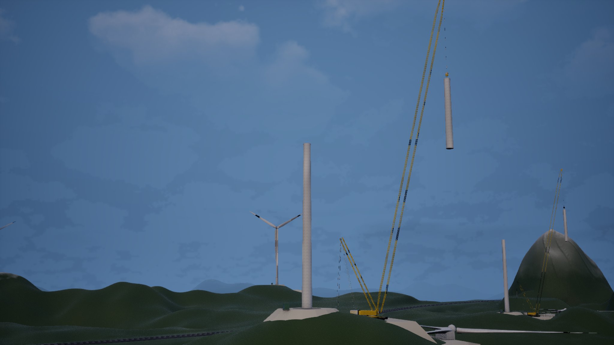 Green hills under a blue evening sky. A yellow crawler crane holds a pale tower section in the air on its cables beside a half-built turbine tower on a concrete pad; a finished three-bladed turbine stands further back and a second crane works on the hill to the right.