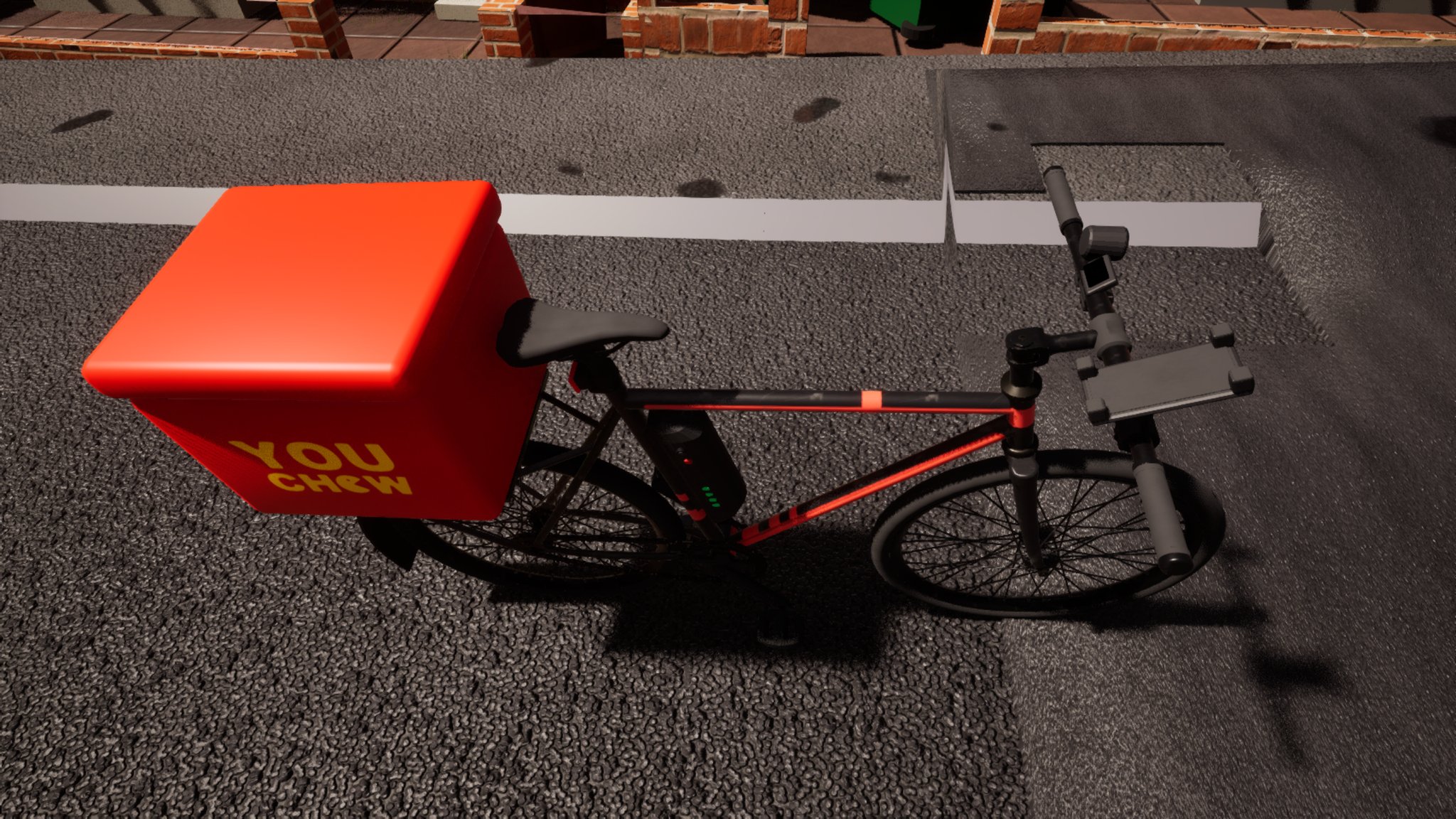An e-bike parked on a tarmac road at night, seen from above and behind. A large red insulated delivery box lettered YOU CHEW in yellow sits on the rear rack, the frame carries a battery pack with green charge lights, and a phone bracket is clamped to the handlebars. A white road line, a drain cover and a low brick garden wall run behind it.