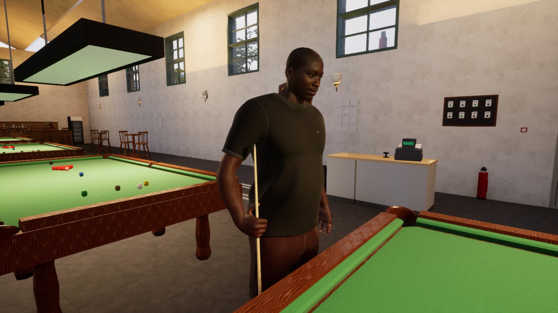 Barry standing between two full-size snooker tables in the Baulk Line with a cue held upright at his side, daylight falling through the north-light roof onto the cloth and high windows down the wall behind him.